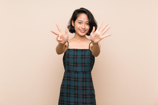 Asian young woman over isolated yellow wall counting eight with fingers