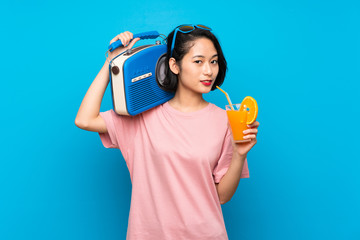 Asian young woman over isolated blue background holding a radio
