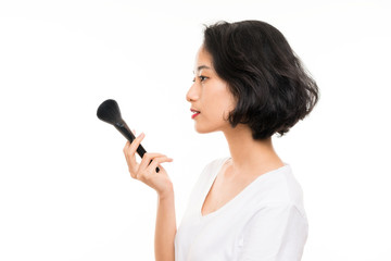 Asian young woman over isolated background with makeup brush