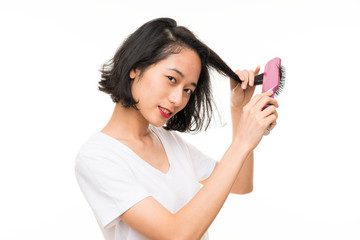 Asian young woman over isolated background with hair comb