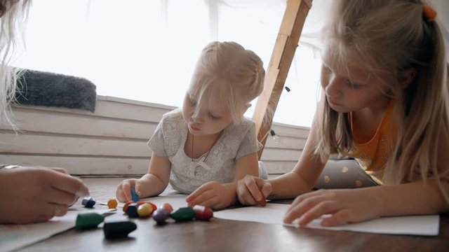 Little girl with they small sister draw paint using multicolored