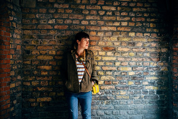 portrait of a young hispter woman against a old bricks wall