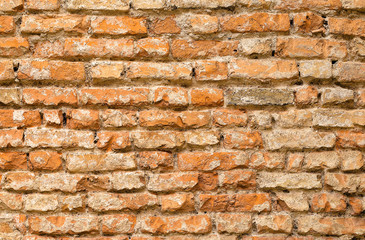 Ancient brick wall texture. Agelong face background. Olden masonry texture. Brickwork with aged bricks, deciduous plaster and pieces of mortar. Variegated run-down wall. Shabby bricking sheet