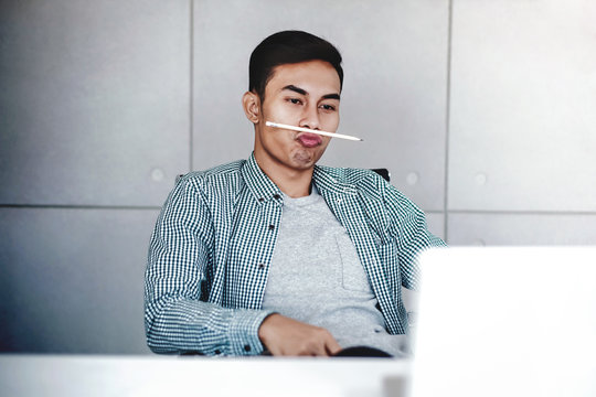Playful Young Businessman Working on Computer Laptop in Office. a Man with Funny Face