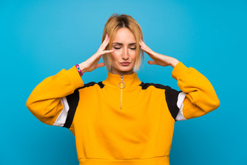 Young blonde woman over isolated blue background unhappy and frustrated with something. Negative facial expression