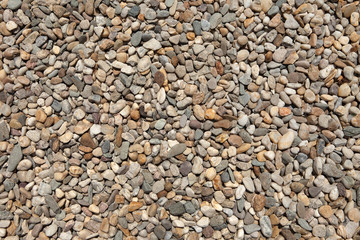 Gravel texture. Small stones, little rocks, pebbles in many shades of grey, white and brown colour. Background of small stones in an oval shape. Texture from little rocks from river or lake