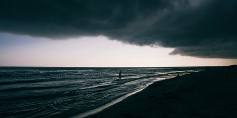 Panoramic widescreen view on the deep blue sea or ocean with dramatic toning on sunset. Big black hurricane clouds. Boundless waving sea. Fascinating and pacifying background.