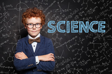 Science concept. Smart child boy on blackboard background with science formulas