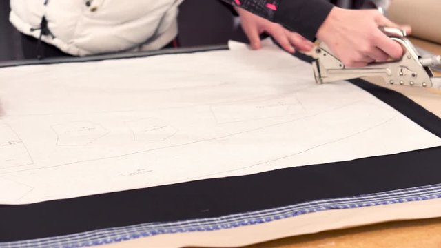 Dressmaker designer stapling and cutting fabric pattern at garment industry . 