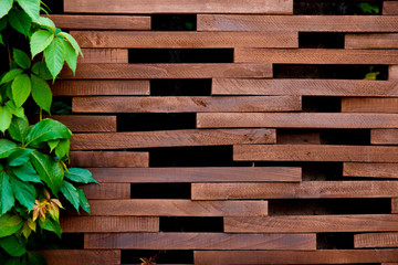 A fence of wooden blocks with green leaves. Wooden texture background