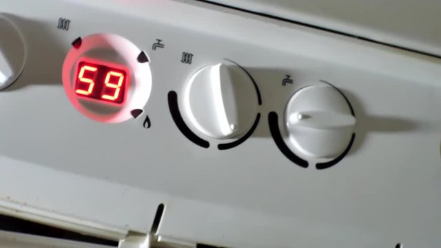 Male hand turning boiler temperature knob up to increase temperature, home comfort. Pan right shot.