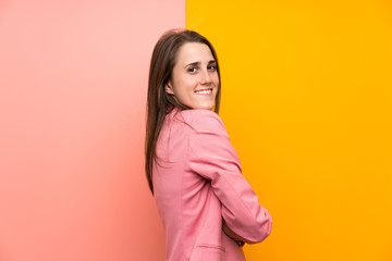 Fototapeta premium Young woman with pink suit over colorful background laughing