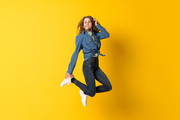 Fototapeta na wymiar Young woman jumping over yellow background