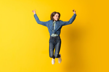 Fototapeta na wymiar Young woman jumping over yellow background