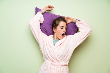 Naklejka premium Young woman in pajama yawning