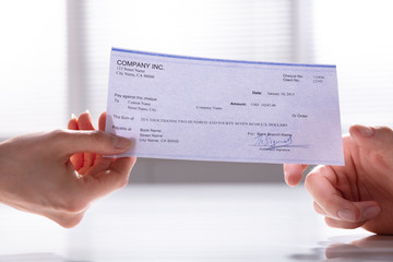 Woman's Hand Giving Cheque To Man