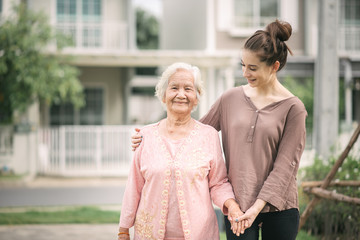 Woman walking and embracing Asian elderly woman