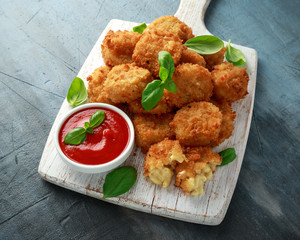 Fried Mac, macaroni and Cheese Bites in breadcrumbs with ketchup sauce on white wooden board