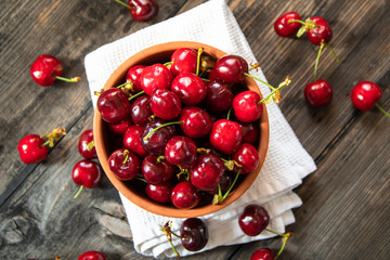 Fresh organic sweet cherries in a clay bowl on old wooden table