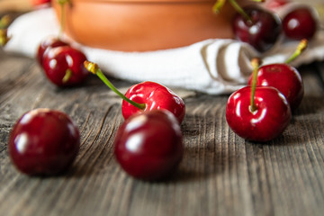 Fresh organic sweet cherries in a clay bowl on old wooden table