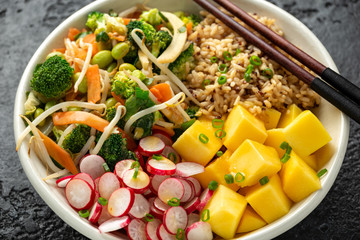 Asian style Vegan salad bowl with edamame, vegetable stir-fry mix, wholegrain rice, quinoa, mango chunks drizzled with mango, chilli dressing