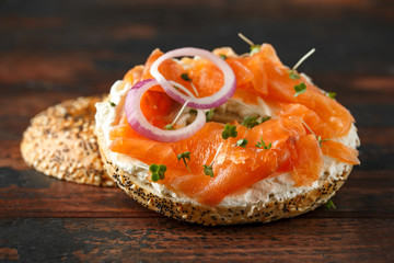 Bagels breakfast sandwich with Cream cheese and salmon on wooden table