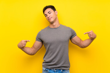 Handsome man over isolated yellow wall proud and self-satisfied