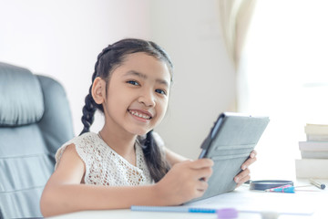 Little Asian girl using tablet and smile with happiness for education concept select focus shallow depth of field