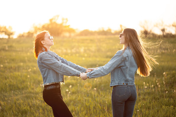 Two young women whirl outdoors in sunset