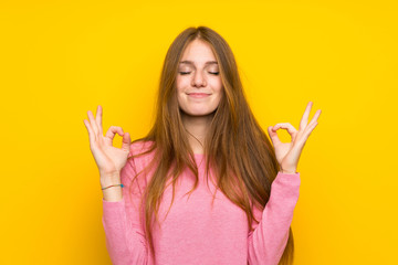Young woman with long hair over isolated yellow wall in zen pose