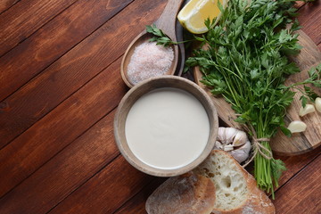 Tahini sauce made from sesame seeds in bowl with parsley on wooden background