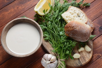 Tahini sauce made from sesame seeds in bowl with parsley on wooden background