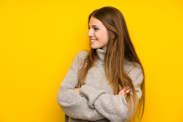 Young woman with long hair over yellow background standing and looking to the side