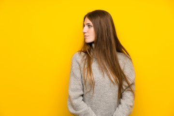 Young woman with long hair over yellow background standing and looking side