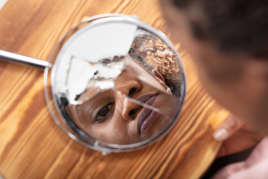 Reflection Of A Woman's Face In Broken Mirror