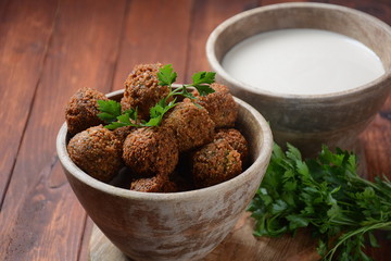 Falafel balls with parsley in wooden bowl with tahini sauce. Vegan healthy food