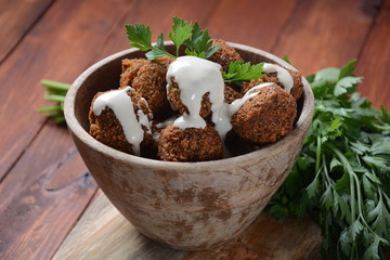 Falafel balls with parsley in wooden bowl with tahini sauce. Vegan healthy food