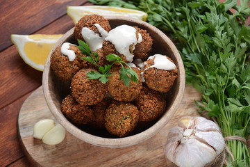 Falafel balls with parsley in wooden bowl with tahini sauce. Vegan healthy food