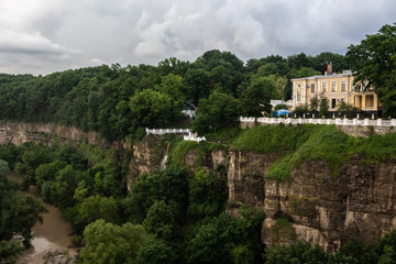 Fototapeta na wymiar Canyon of the Smotrych River in Kamianets-Podilskyi, covered with green forest, after rain. The river is visible below. Ukraine.