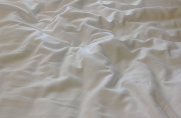 White messy sheets on unmade background. Wrinkled linen on hotel bed 