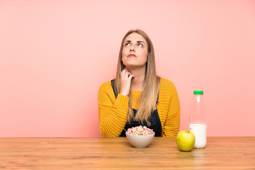 Young woman with bowl of cereals standing and thinking an idea