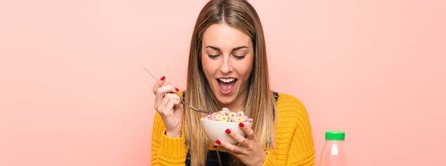 Young woman with bowl of cereals over pink wall