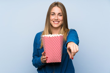 Obraz premium Blonde woman with popcorns over blue wall