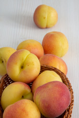 Close-up of apricots in basket on white wooden background