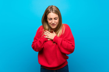 Woman with red sweater over blue wall having a pain in the heart