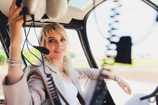 Female pilot in cockpit of helicopter before take off. Young woman helicopter pilot.