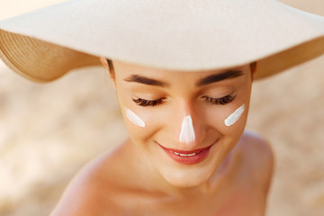 Beauty Woman smile applying sun cream on face. Skin care. Body Sun protection. sunscreen. Female in hat smear moisturizing lotion on skin