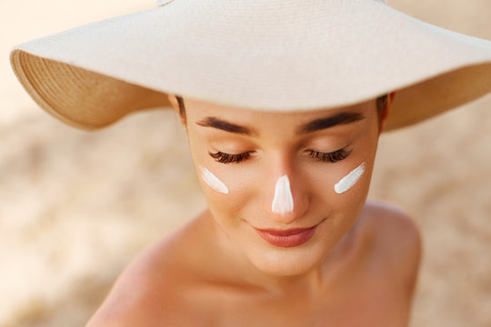 Beauty Woman smile applying sun cream on face. Skin care. Body Sun protection. sunscreen. Female in hat smear moisturizing lotion on skin