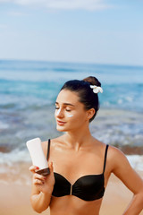 Suntan Lotion. Sexy Young Woman in Bikini  Applying Sunscreen Solar Cream.Sun Protection. Sun Cream. Skin and Body Care.Girl Holding Moisturizing Sunblock. Sun shape on the shoulder. Skin Protection