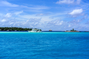 An island in the Maldives is a landscape of an ocean beach and a ship. Bright blue sky and ocean.